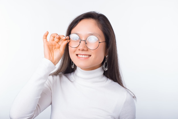 Smiling girl is daydreaming while wearing glasses over white.