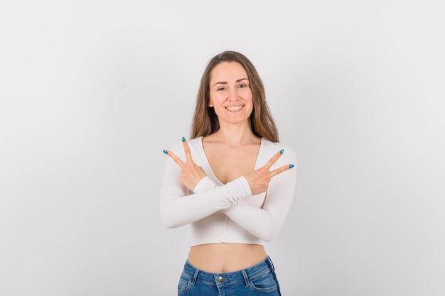 Smiling girl is looking at camera by crossing hands on white background