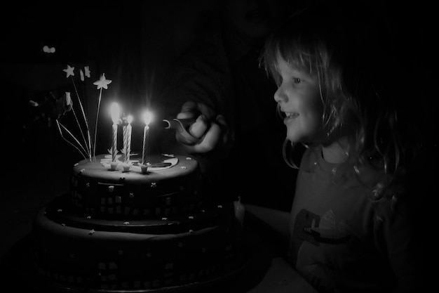 Photo smiling girl looking at cake during birthday