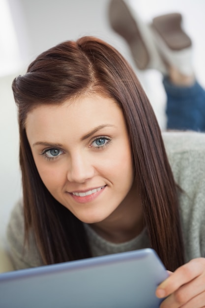 Smiling girl looking using a tablet pc on sofa