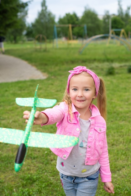 A smiling girl plays with an airplane in the open air