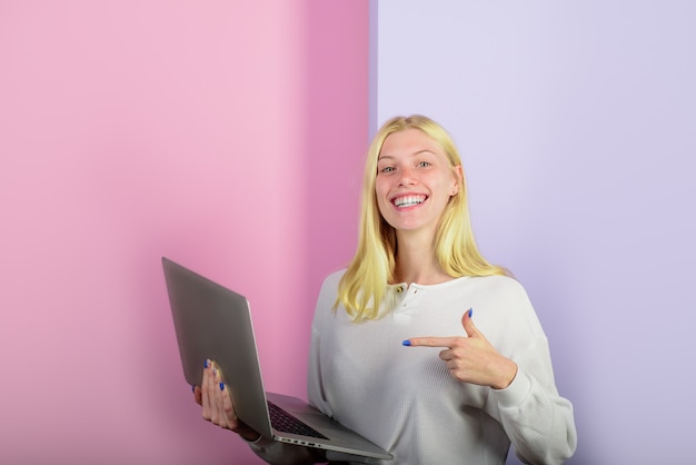 Smiling girl pointing finger on personal computer woman shows finger on laptop computer student girl