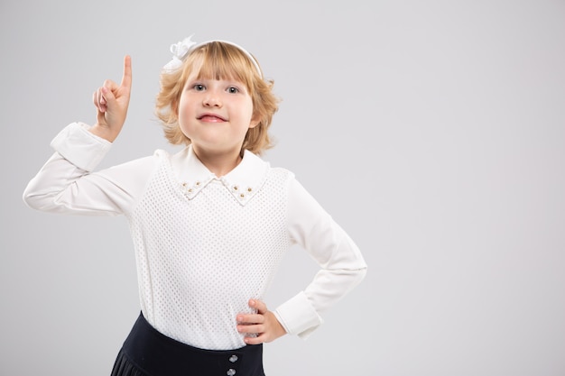 A smiling girl points her finger at the free space. Advertising space. Bright emotion.