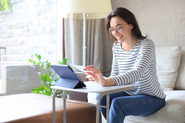 Smiling girl sit on couch watching webinar on laptop. Happy young woman study on online distant course.