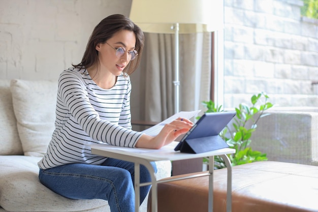 Smiling girl sit on couch watching webinar on laptop Happy young woman study on online distant course