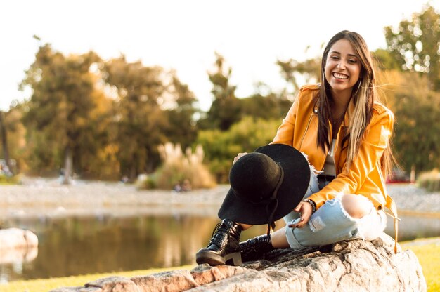 Smiling girl sitting on a rock with a natural landscape in the background