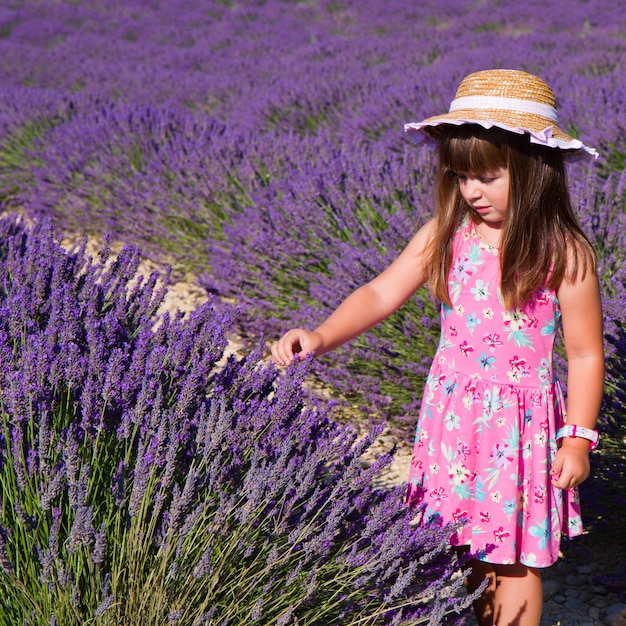 La ragazza sorridente che fiuta fiorisce in un giacimento della lavanda