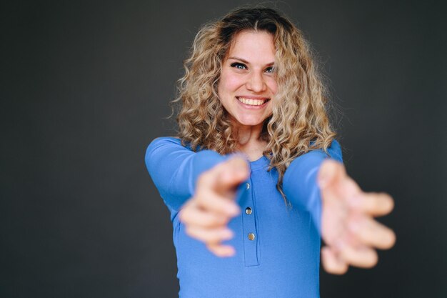 Foto la ragazza sorridente allunga le mani in avanti su uno sfondo semplice