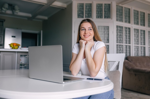 Smiling girl student with laptop taking notes in a notebook si