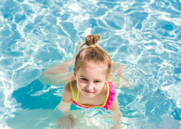 Smiling girl swim to the poolside