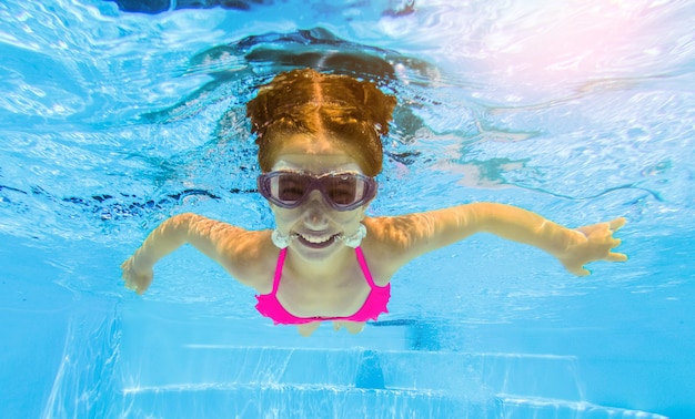 Smiling girl swimming underwater in pool