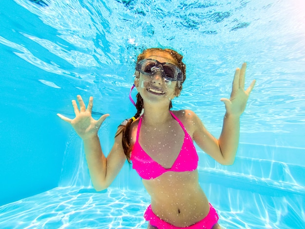 Smiling girl swimming underwater in pool