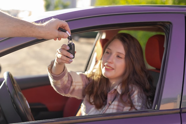 Una ragazza sorridente prende la chiave dell'auto vendita e acquisto di auto concessionaria auto