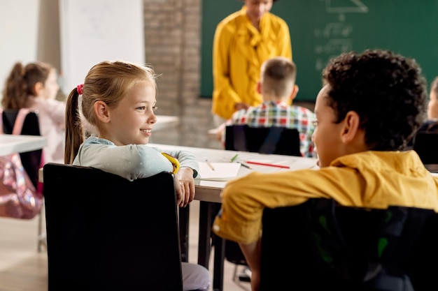 Photo smiling girl talking to her classmate in the classroom