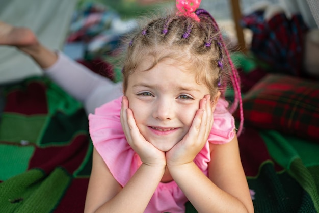 Ragazza sorridente in tenda bambino che gioca in tenda bambini campeggio divertendosi all'aperto campeggio faccia buffa clos