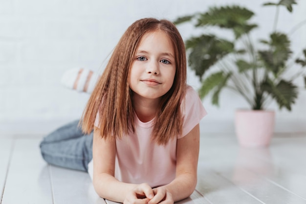 Smiling girl thinking looking at camera in room at home