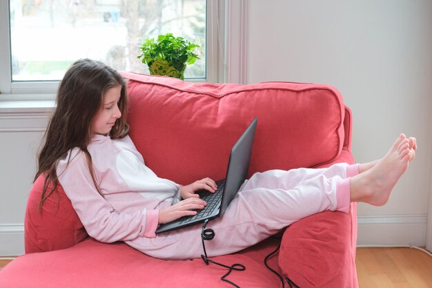 Smiling girl using laptop while sitting on sofa at home