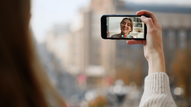 Foto ragazza sorridente che agita una videoconferenza sullo schermo dello smartphone in primo piano amici che chattano sul web