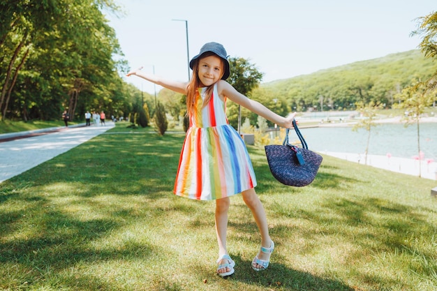 日当たりの良い夏の公園で腕を伸ばして風に手を振っている笑顔の女の子