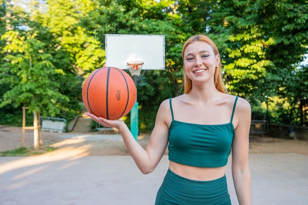 Photo a smiling girl with a basketball in a basketball court ready to play