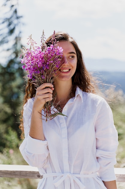 花と笑顔の女の子。森の中で花束を持つ少女の肖像画。