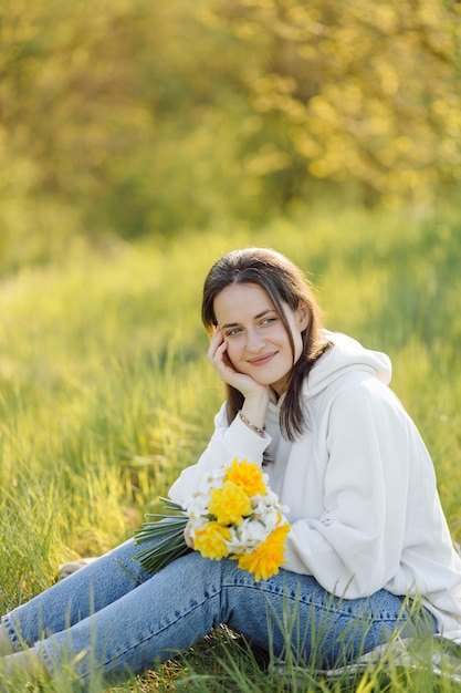 Smiling girl with flowers walking in the woods