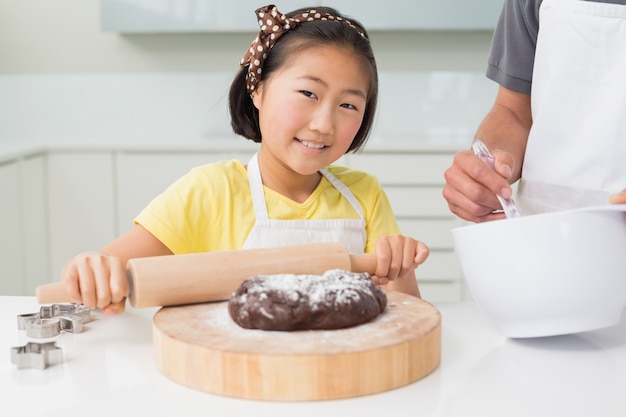 Smiling girl with her father preparing cookies in kitchen