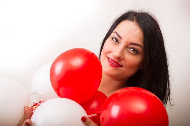 Ragazza sorridente con palloncini di palline rosse e bianche