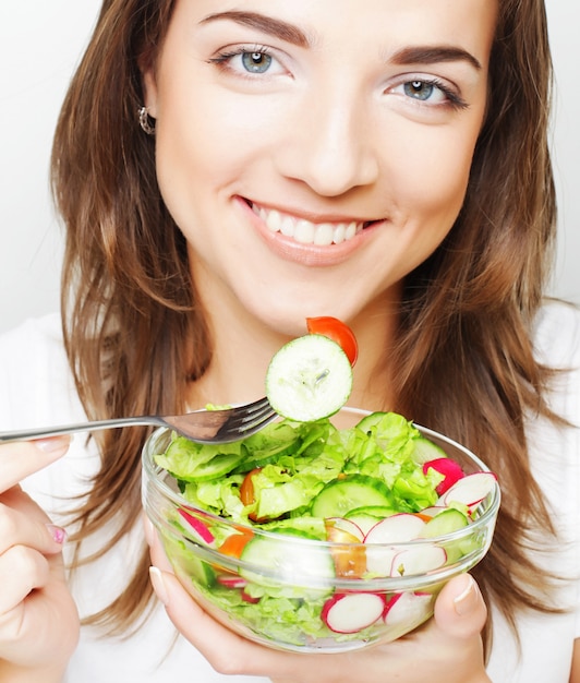 Foto ragazza sorridente con insalata su una priorità bassa bianca