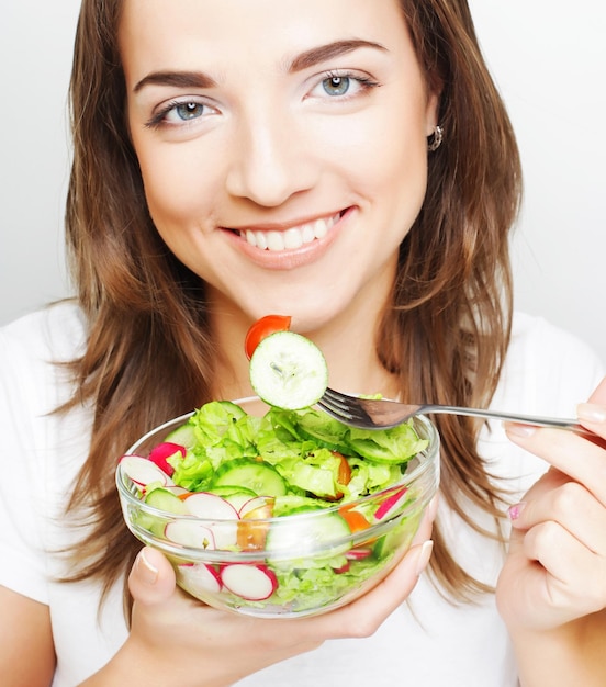 Smiling girl with a salad on a white background