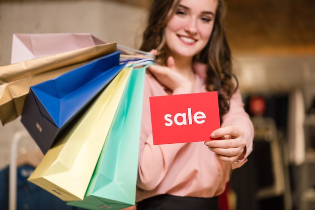 Smiling girl with shopping bags and sale sign