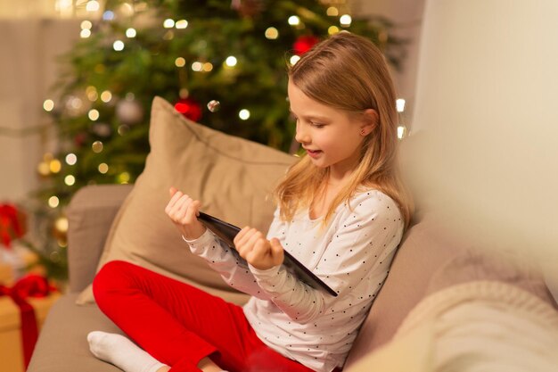 smiling girl with tablet pc at christmas home