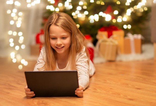 クリスマスの家でタブレットPCを持った笑顔の女の子