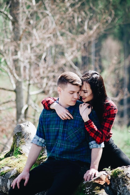 Smiling girlfriend embracing boyfriend in forest