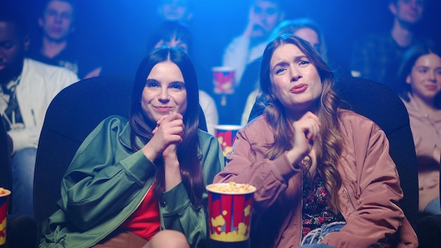 Smiling girls spending time in movie theater Women looking film in cinema