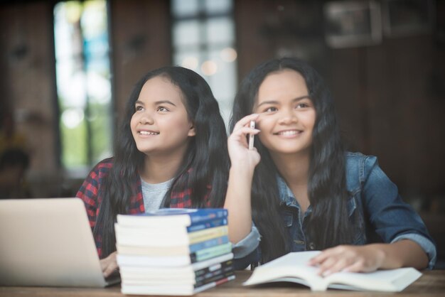 写真 テーブルに座って携帯電話を使っている笑顔の女の子