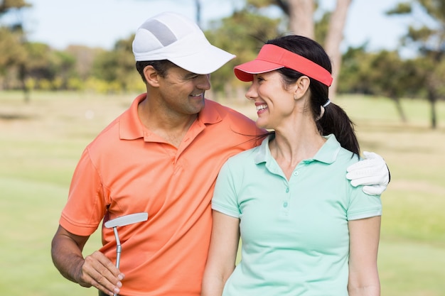 Smiling golfer couple with arm around