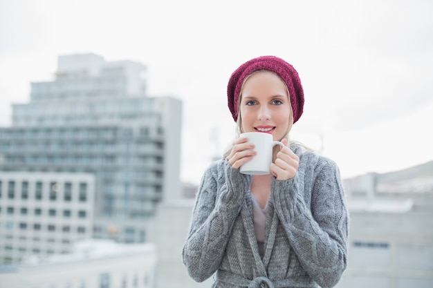 Smiling gorgeous blonde holding coffee outdoors