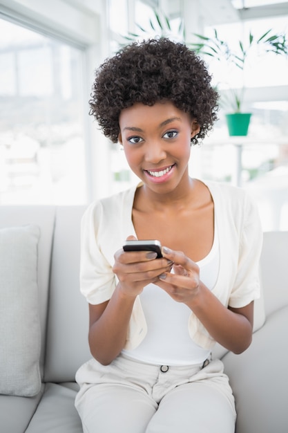 Smiling gorgeous brunette using her smartphone