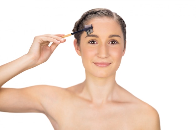 Smiling gorgeous model using eyebrow brush