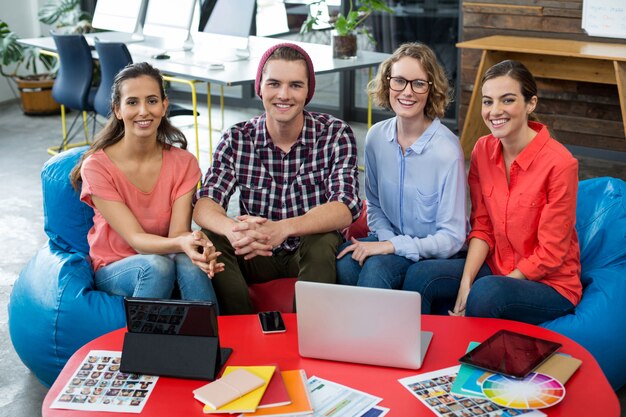 Smiling graphic designers sitting in office with laptop and digital tablet on table