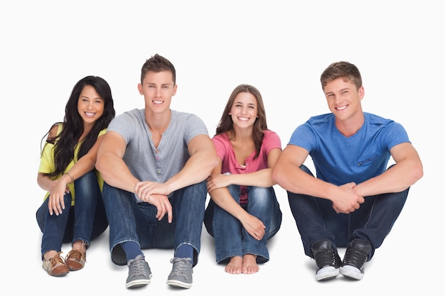 Smiling group sitting on the ground with their hands on their legs