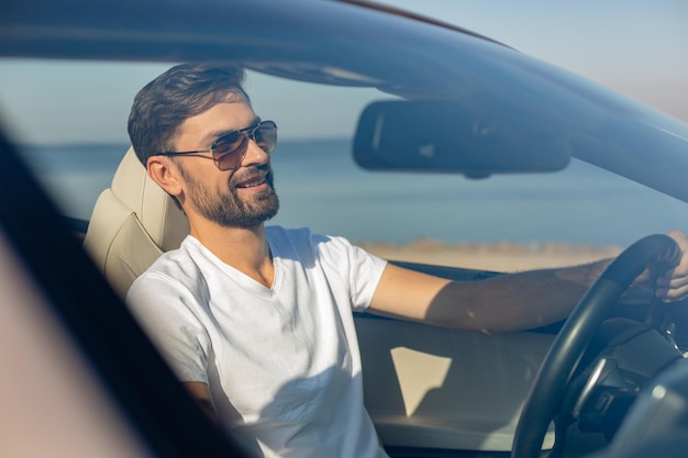 Smiling guy driving cabriolet on the road