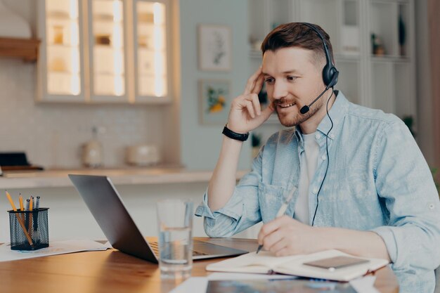 Smiling guy listening attentively online lesson while sitting at home