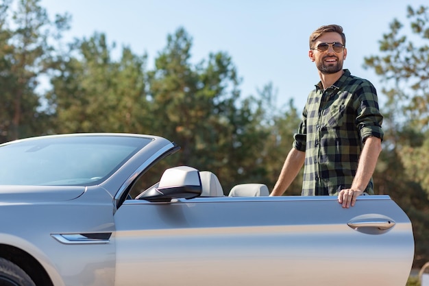 Smiling guy standing at the convertible with open door