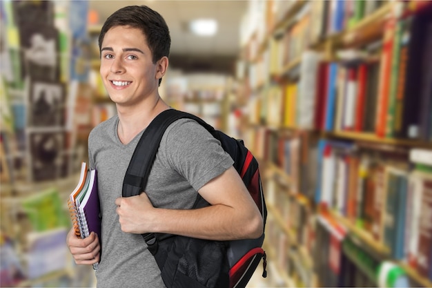 Smiling handsome boy with books on  background