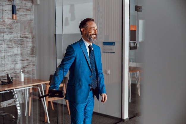 Smiling handsome businessman entering the door in office