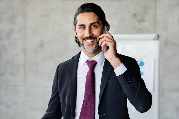 Smiling handsome businessman talking on phone at office