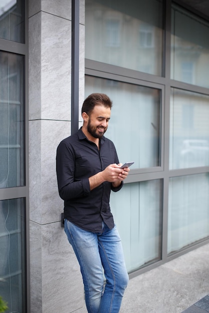 Un bell'uomo d'affari sorridente con la barba va a parlare con i suoi clienti per telefono