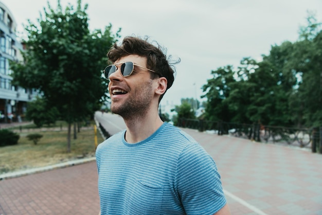 Smiling and handsome man in tshirt and glasses looking away